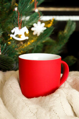 Obraz na płótnie Canvas Blank red mug with christmas tree and piano on background,mat tea or coffee cup with christmas and new year decoration,vertical mock up with ceramic mug for hot drinks,empty gift print template.