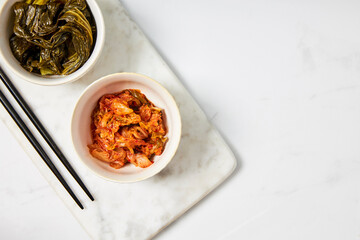 Top view of kimchi and fermented bok choy served in two white bowls