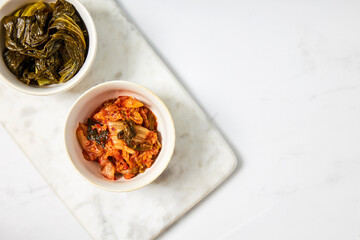 Top view of kimchi and fermented bok choy served in two white bowls