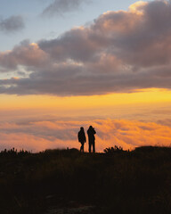 Fototapeta na wymiar silhouette of people enjoying sunset in the mountains above the clouds, adventure