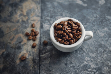 Coffee beans in cup on stone background