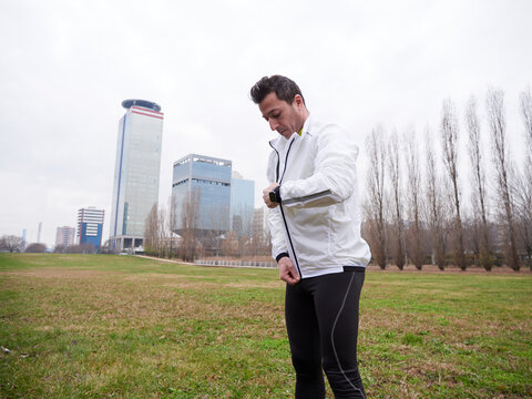 Adult Man running in the parc in winter with city background