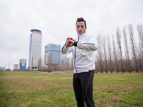 Adult Man running in the parc in winter with city background