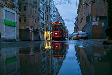 Fototapeta na wymiar Old nostalgic tram going through the streets of European side of Istanbul. Vintage red tram in Taksim. winter landscape, snowy roads
