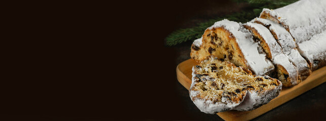 Christmas stollen on wooden background. Christmas Stollen cake and bokhe. Traditional hand made german christmas stollen. Banner. Copy space