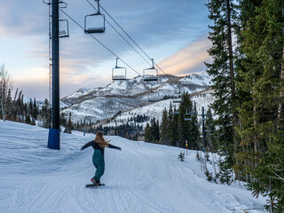 blonde woman snowshoeing on ski hill at sunset