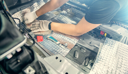Auto service worker installs soundproofing material inside car interior, soundproofing insulation.