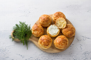 Cheese profiteroles with cream cheese, cucumber and herbs, gougeres, traditional French pastries,...