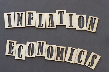 the expression (sign) "inflation economics" in wooden stencil font on paper