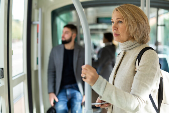 Portrait of thoughtful mature woman riding in modern streetcar. Concept of daily city commuting