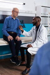 Obraz premium Practitioner physician doctor holding lungs radiography of retired old man discussing sickness symptoms explaining healthcare treatment in hospital office. Senior patient having medical appointment