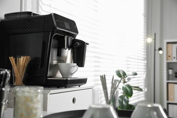 Modern coffee machine with cup in office. Space for text