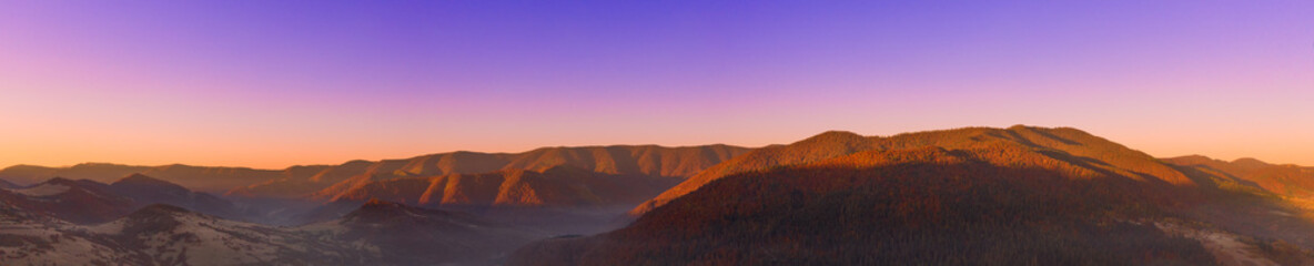 Autumn mountain landscape panorama. Peaks above the fog. Drone view.
