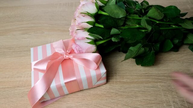 closeup female hands holding box with gift, bouquet of white, pink roses, box with gift with satin ribbon, flowers for professional holiday, concept of mother's, Valentine's day, birthday
