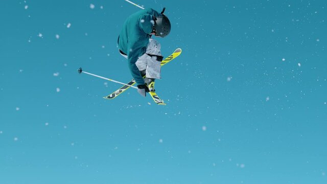 SLOW MOTION, CLOSE UP Action shot of an expert freestyle skier taking off a kicker and doing a 360 grab while exploring , Slovenia. Skier riding in the mountains of Slovenia does a cool trick.