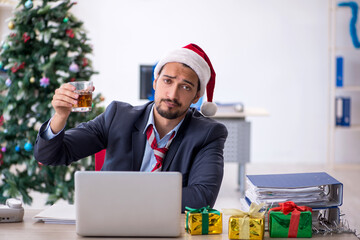 Young male employee celebrating Christmas at workplace