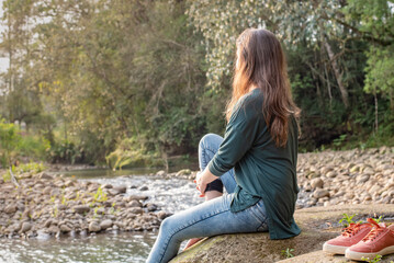 Woman sitting on a rock holding her leg. Woman relaxing in nature