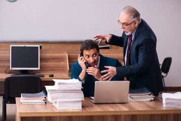 Old male employer and young male assistant in bullying concept