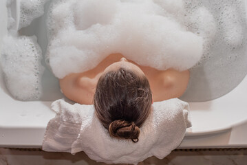 Woman relaxing in hot bath tub with soap foam