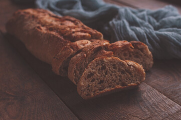 Baked homemade bread on wooden table with a gray gauze tablecloth