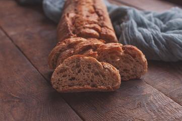 Baked homemade bread on wooden table with a gray gauze tablecloth