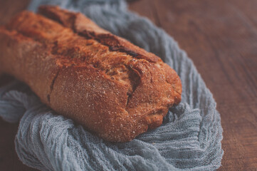Bread on a wooden table with a gray gauze tablecloth