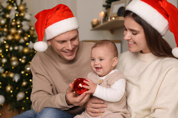 Happy couple with cute baby in room decorated for Christmas