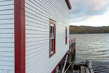 A vintage white wooden building near the water's edge overlooking the blue ocean. The storage...