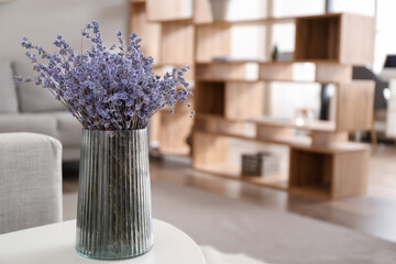 Vase with beautiful lavender flowers on table in room