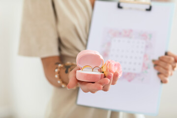 Female wedding planner with rings and Save the Date Announcement in office, closeup