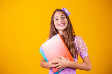 Beautiful smiling girl holding books going to school. close up portrait, isolated yellow background, childhood. child hugging notebooks. lifestyle, interest, hobby, free time, free time