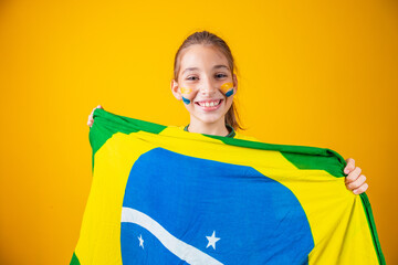 small caucasian girl with brazil flag on yellow background. Brazilian child supporter