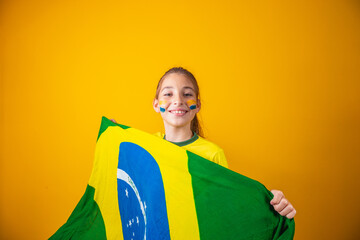 small caucasian girl with brazil flag on yellow background. Brazilian child supporter