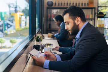 businessman working on counter by window in coffee shop