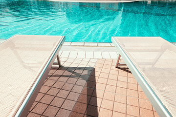 Resort pool. Summer resort chair, relax lounge at luxury hotel pool. Beach lounger chaise. Vacation sunbed. Blue water, sunny happy travel holiday.