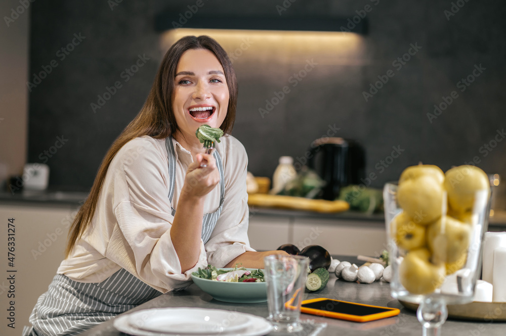 Wall mural Smiling happy woman eating with appetite