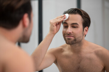 Handsome man cleansing his face with a sponge