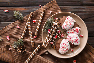 Plate with tasty candy cane cookies on dark wooden background