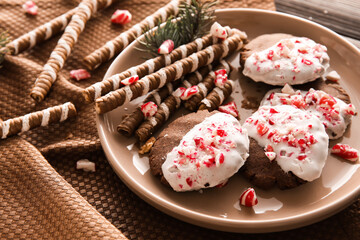 Plate with tasty candy cane cookies on table