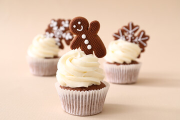 Tasty Christmas cupcakes with gingerbread cookies on beige background