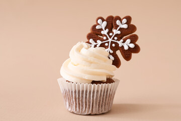 Tasty Christmas cupcake with gingerbread cookie on beige background