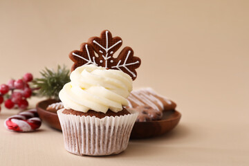 Tasty Christmas cupcake with gingerbread cookies on beige background