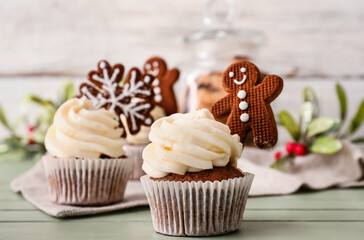 Tasty Christmas cupcakes with gingerbread cookies on table