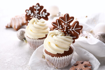 Tasty Christmas cupcakes with gingerbread cookies on light background