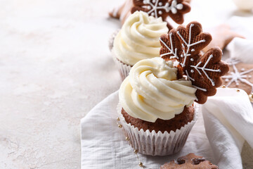 Tasty Christmas cupcakes with gingerbread cookies on light background