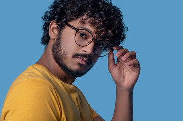 Serious man in round eyeglasses looking ahead