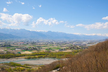 Fototapeta na wymiar 新緑の季節の長野県安曇野の町並みと,北アルプスを高台から望む