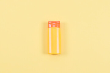 Sun cream lies in the middle of a light yellow background.
