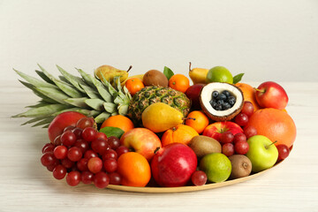Platter with different fresh fruits on white wooden table