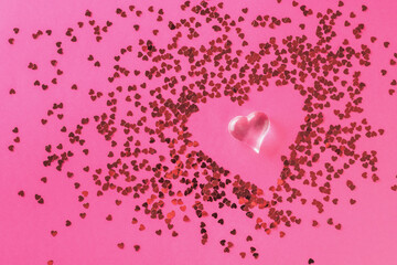 A figurine of a glass heart on an abstract background of many small hearts. The concept of Valentine's Day.